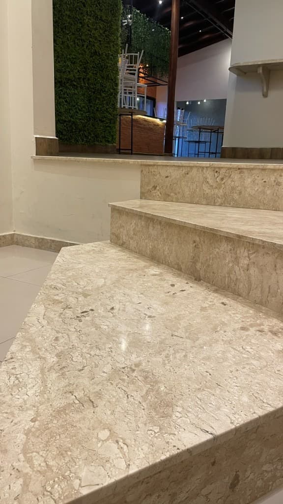 Escada em mármore com parede verde e vista para o salão