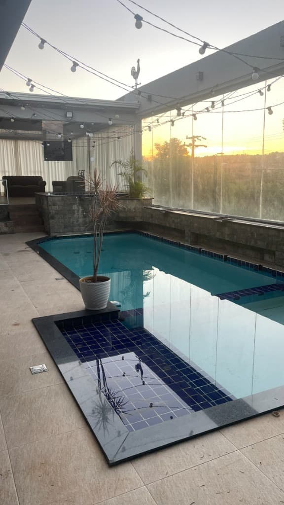 Piscina ao entardecer com luzes de festa e vista para o pôr do sol