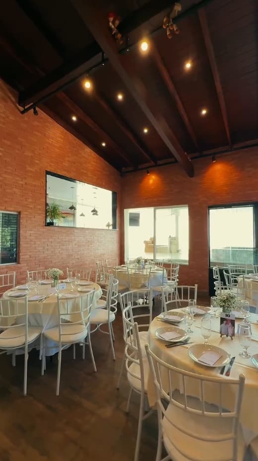 Salão montado para casamento com cadeiras Tiffany e flores brancas