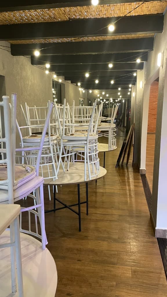 Corredor do salão com mesas, cadeiras e luzes de festa no teto